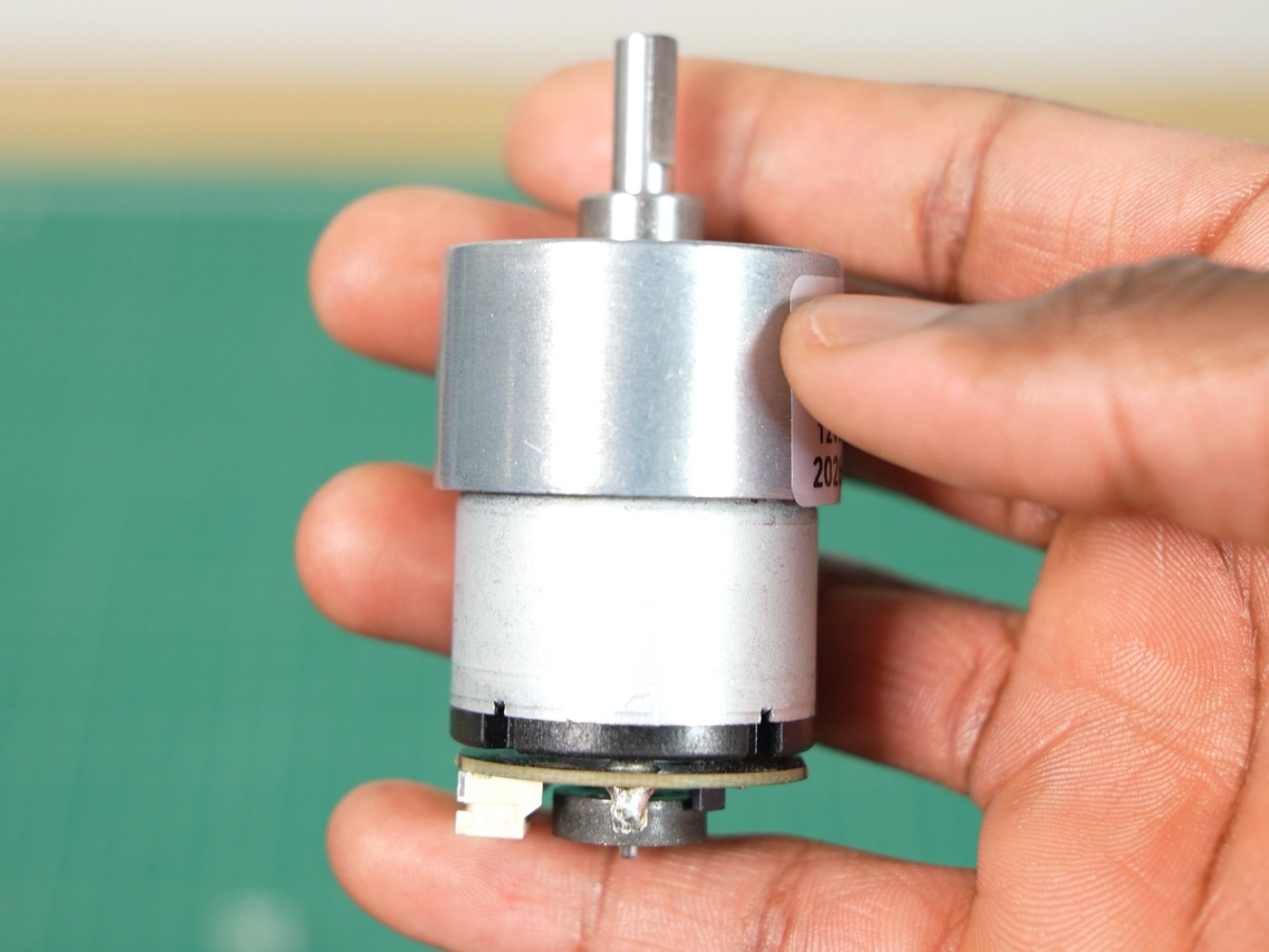 JGB37-520 geared DC motor held in a hand, with the encoder board on the back of the motor