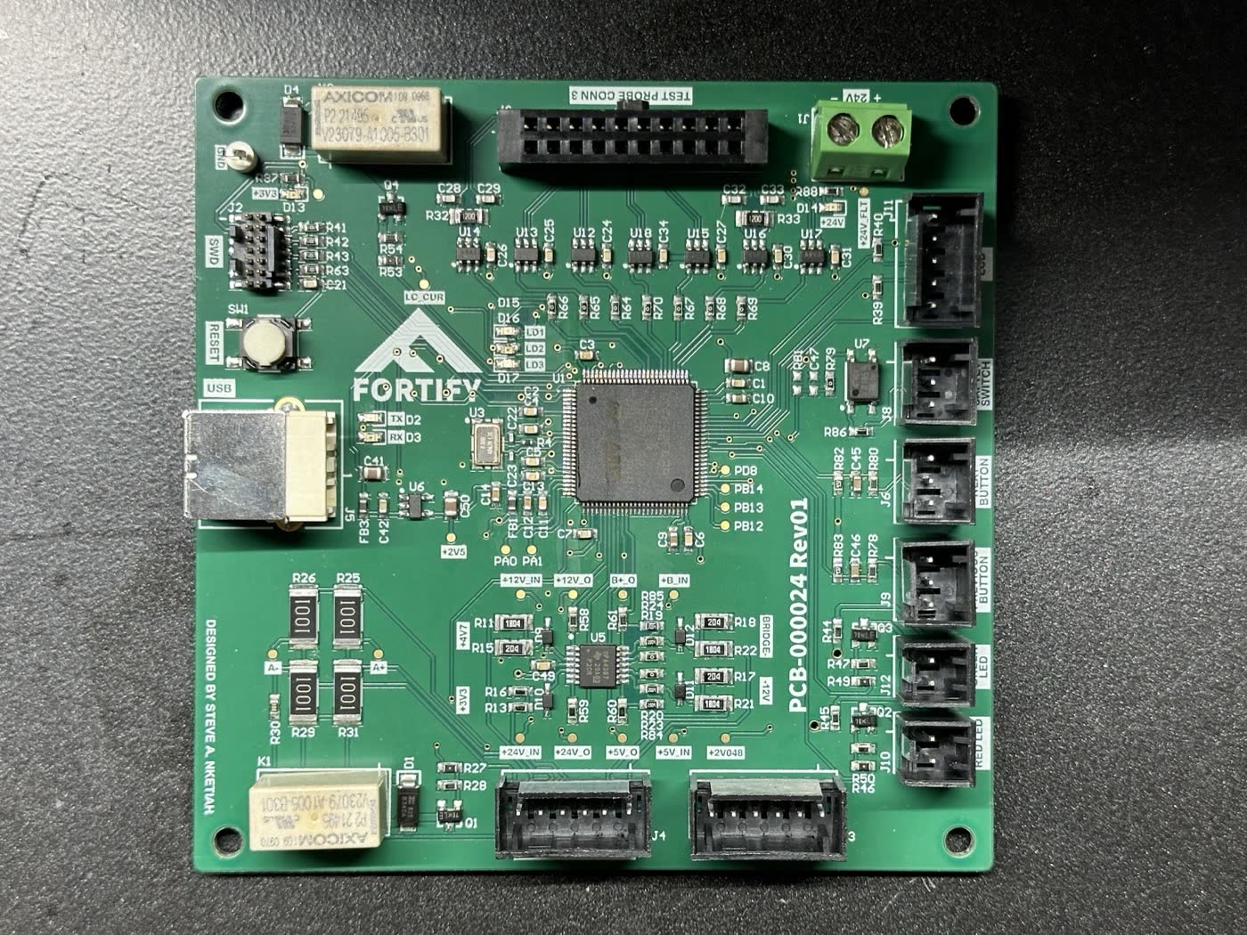 Assembled green test fixture PCB with the STM32F429 in the centre and connectors around the edges